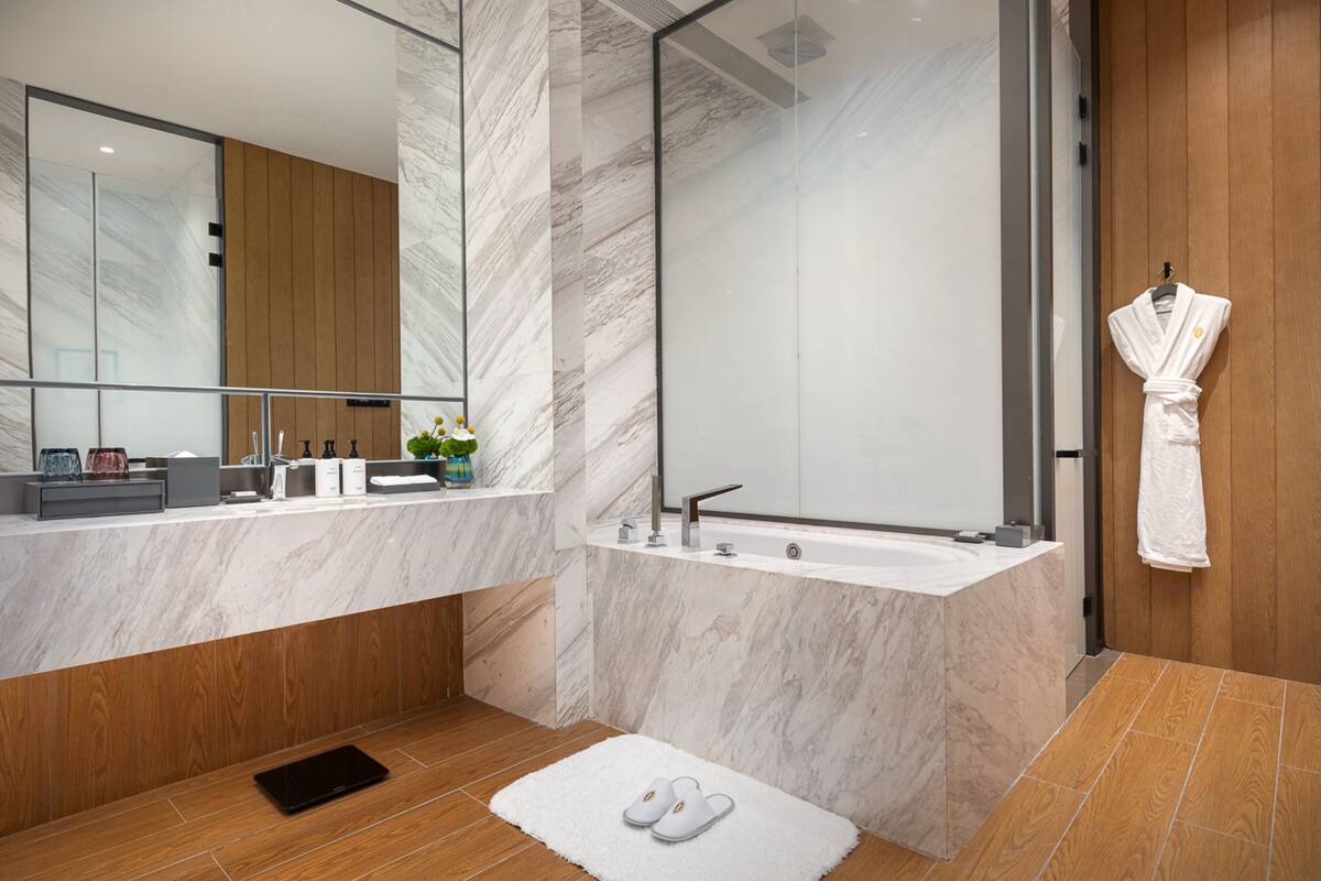 Une salle de bain moderne avec un meuble-lavabo en marbre, une baignoire sur pieds et un mur revêtu de panneaux en bois.