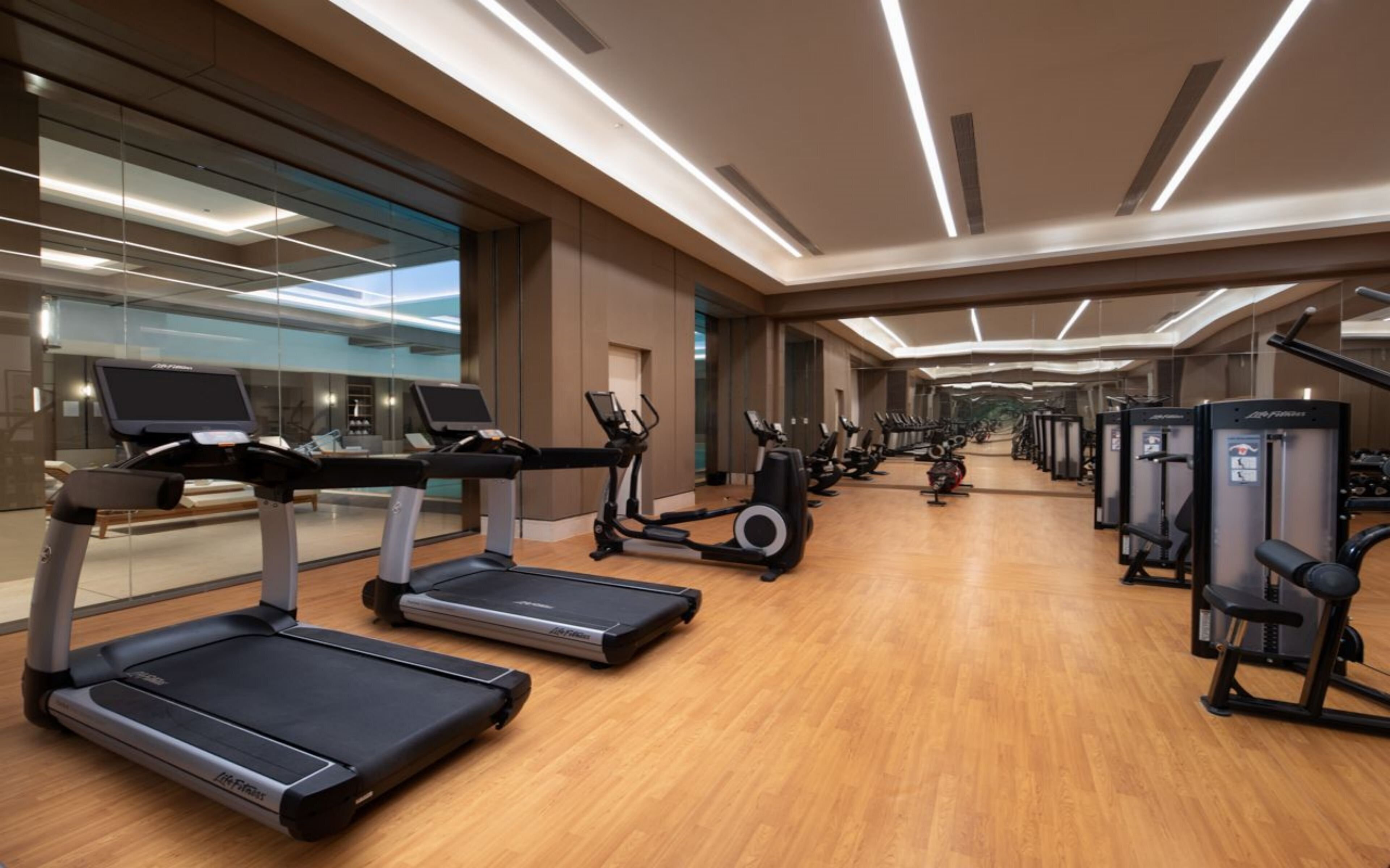 Un gimnasio moderno con cintas de correr, elípticas y equipo de pesas.