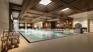 A spacious indoor swimming pool with wooden ceiling beams, lounge areas, and modern lighting fixtures. - Intercontinental Chongli by IHG (Zhangjiakou)