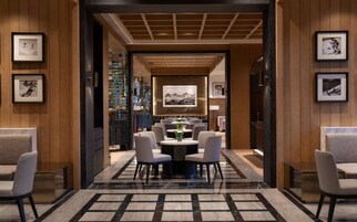 Un moderno vestíbulo de hotel con piso de mármol, una mesa redonda central y asientos a ambos lados.