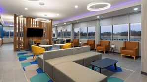Ein moderner Lounge-Bereich mit Sitzgelegenheiten, einem Flachbildfernseher und großen Fenstern mit Blick ins Freie.
