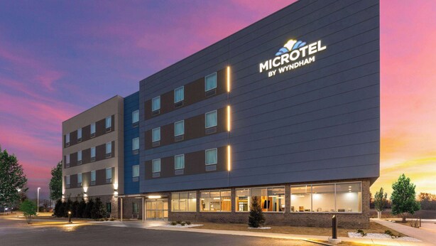 Ein modernes Microhotel mit flacher Fassade, zahlreichen Fenstern und einem gut sichtbaren Logo.
