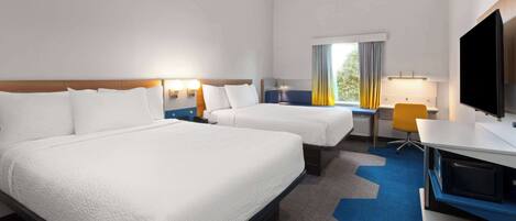 A hotel room with two beds, a desk, a chair, a TV, and a window with curtains.
