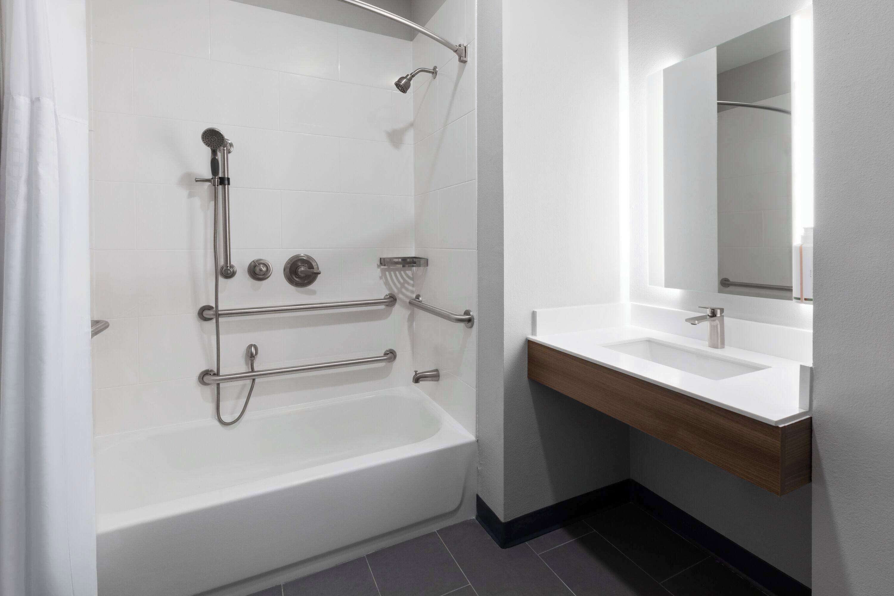 A modern bathroom with a bathtub, shower, and a vanity with a mirror.