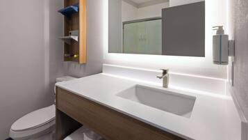 Un baño moderno con un lavabo blanco, tocador de madera y un espejo sobre el lavabo.
