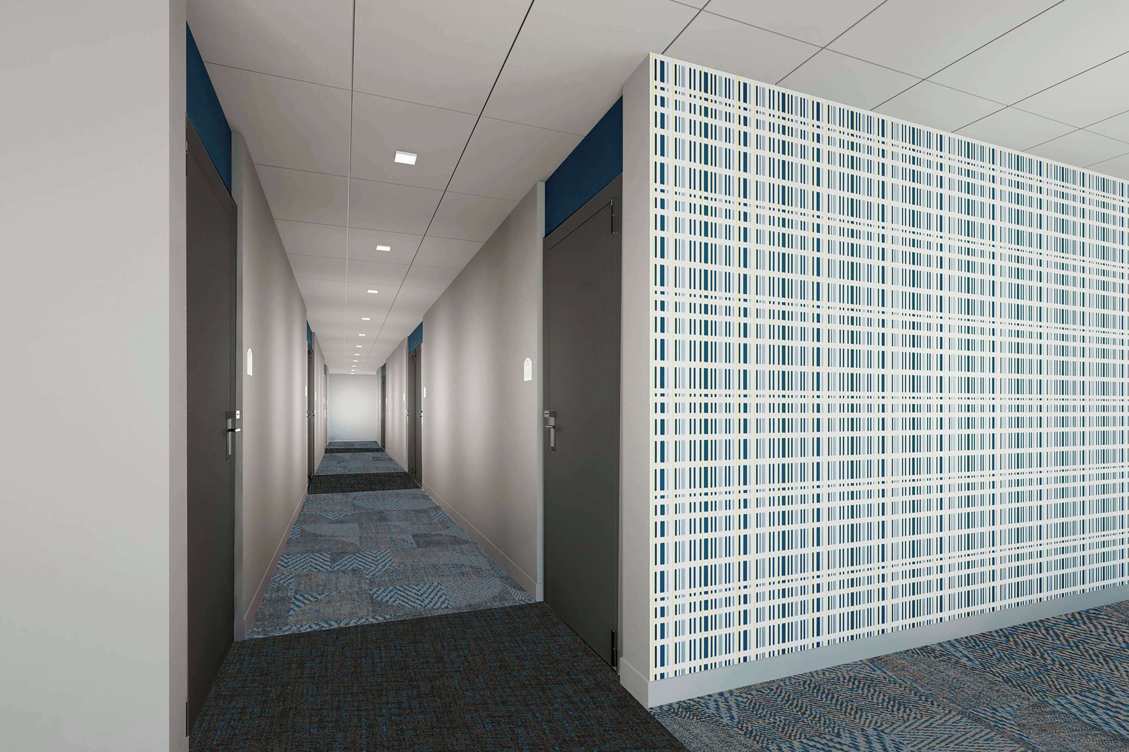 A corridor with patterned carpet, white walls, and a blue and white partition.