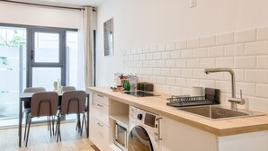 A modern kitchen with a built-in washing machine, a sink, and a dining area with chairs.