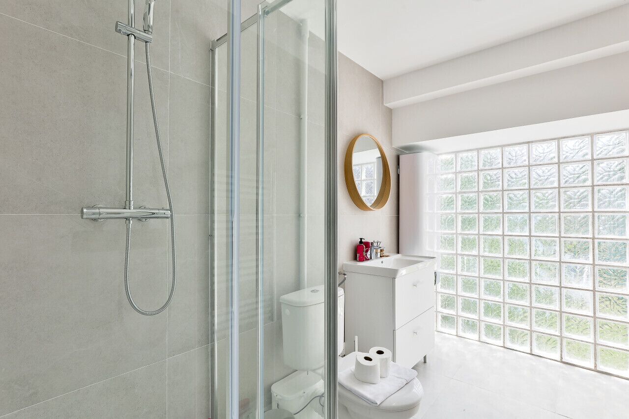 Een moderne badkamer met een douchecabine van glas, een toilet en een wastafel met spiegel.