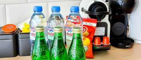 A kitchen counter with various items including bottles of Evian water, a coffee maker, and a Krups electric kettle.