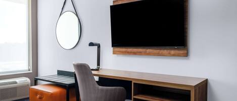 A modern office space with a desk, chair, and a large flat-screen TV mounted on the wall.