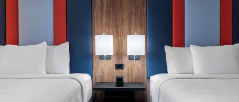 A hotel room with two beds, a wooden accent wall, and two wall-mounted lamps.