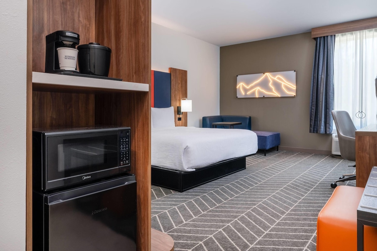 A hotel room with a bed, a microwave, a coffee maker, a desk, and a seating area.