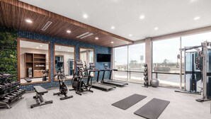 A modern gym with cardio equipment, weight machines, and a large mirror. - La Quinta by Wyndham Chelsea Birmingham (Chelsea)