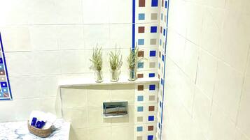 Een badkamer met toilet, een wastafel met een marmeren blad, een kleine plant en een douche.
