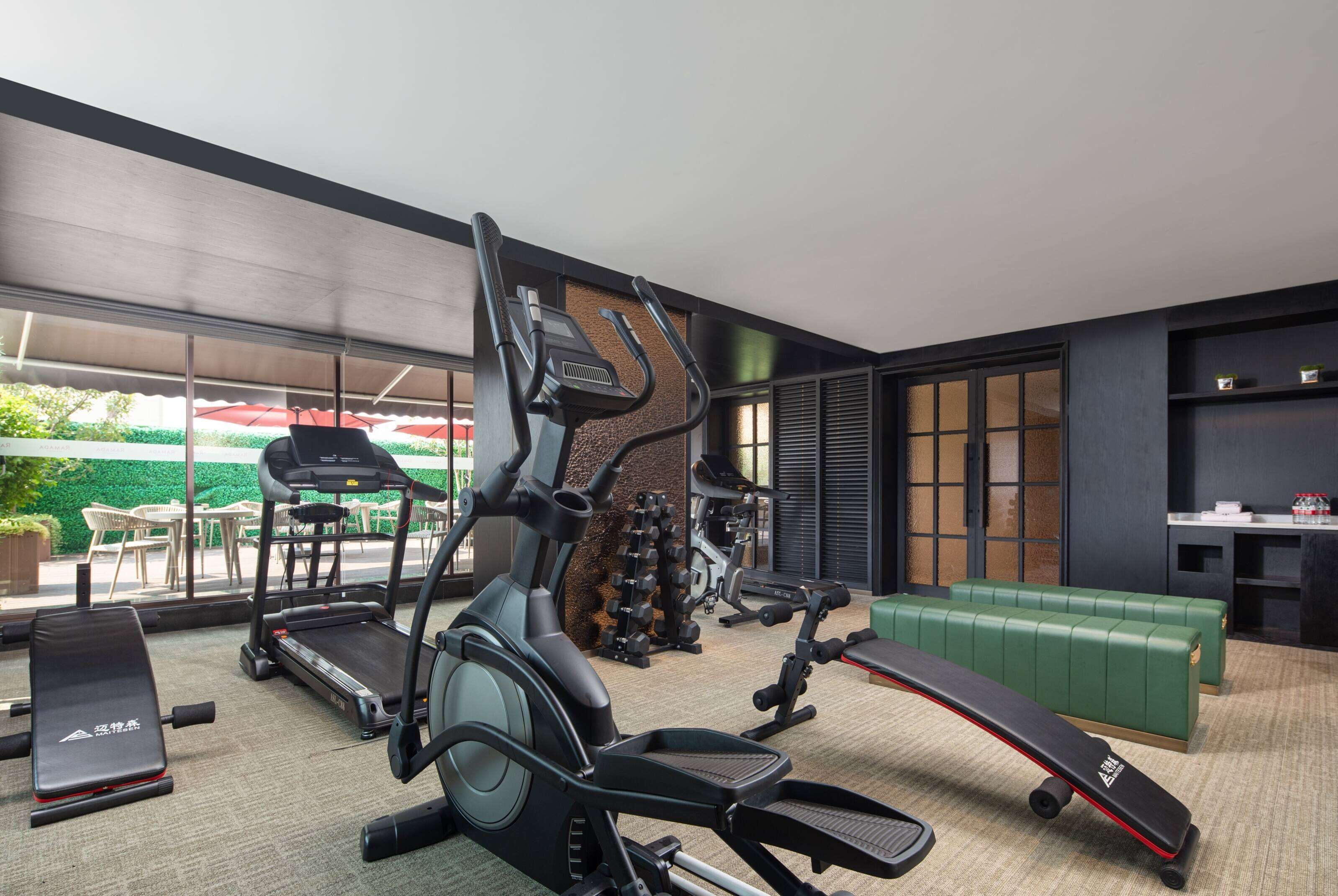 Et moderne fitnesscenter med løbebånd, vægtaftræningsbænke og et grønt loungeområde.