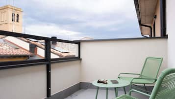 Un balcón con vistas a edificios, una mesa con sillas y un par de gafas de sol sobre la mesa.
