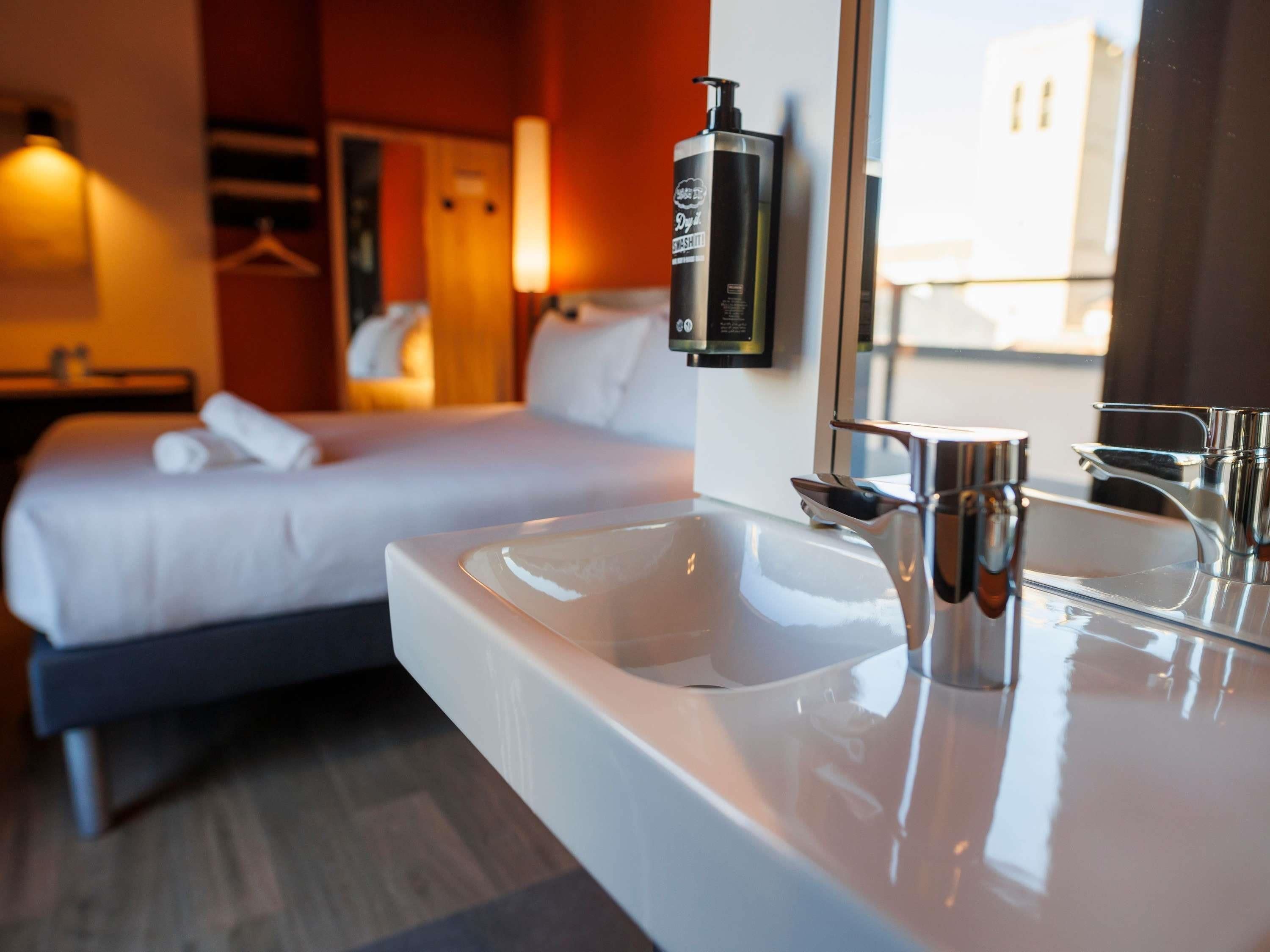 Een hotelkamer met een bed, een wit wastafelmeubel en een spiegel.