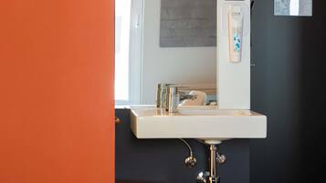 Un baño moderno con lavamanos blanco, accesorios de cromo y un espejo.