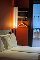 Habitación de hotel con cama, lámpara colgante y vista al balcón.