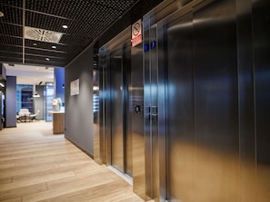 A modern elevator with a digital display, a no smoking sign, and a sign indicating no smoking in the elevator.