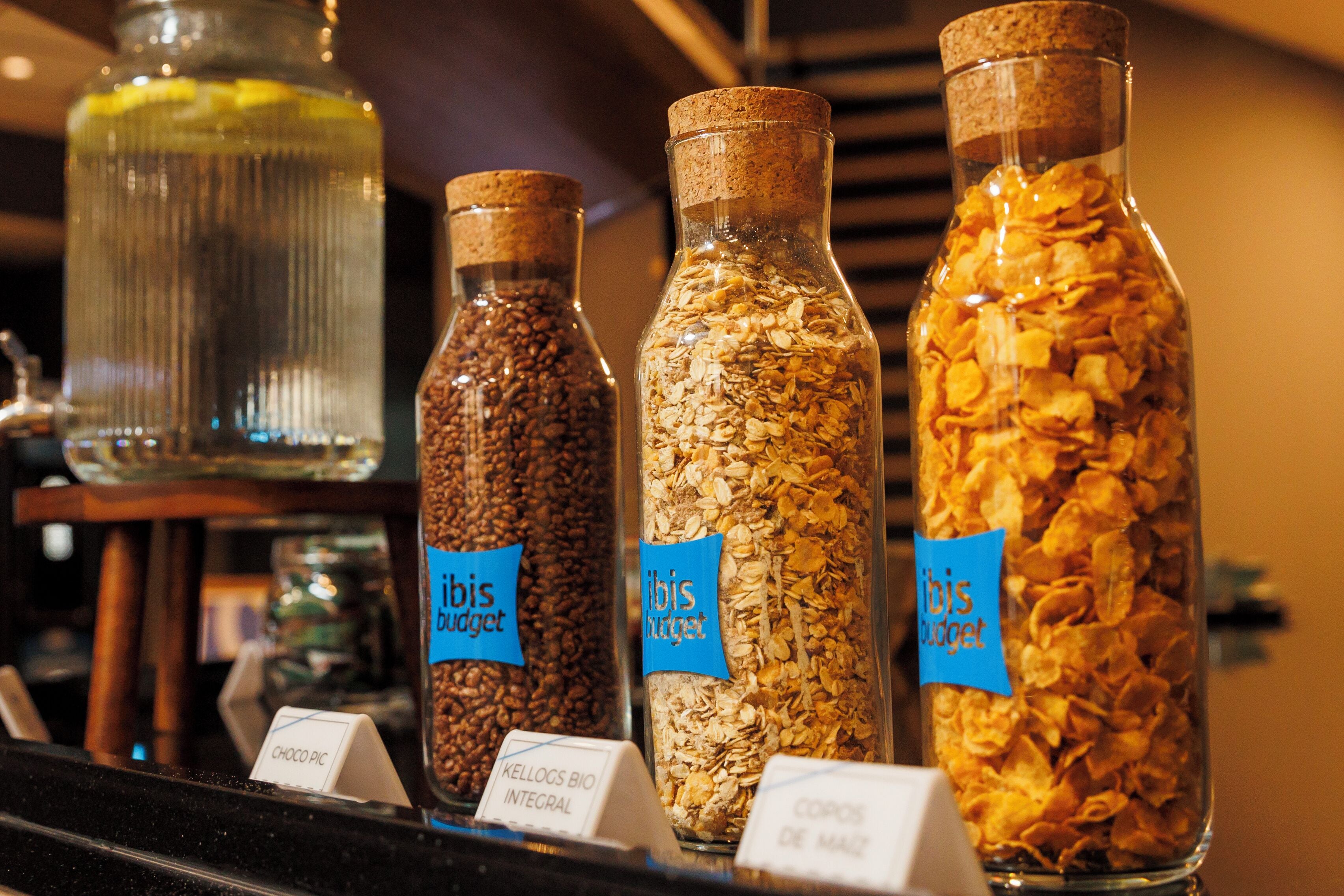 Três garrafas de vidro com etiquetas, cada uma contendo diferentes alimentos.
