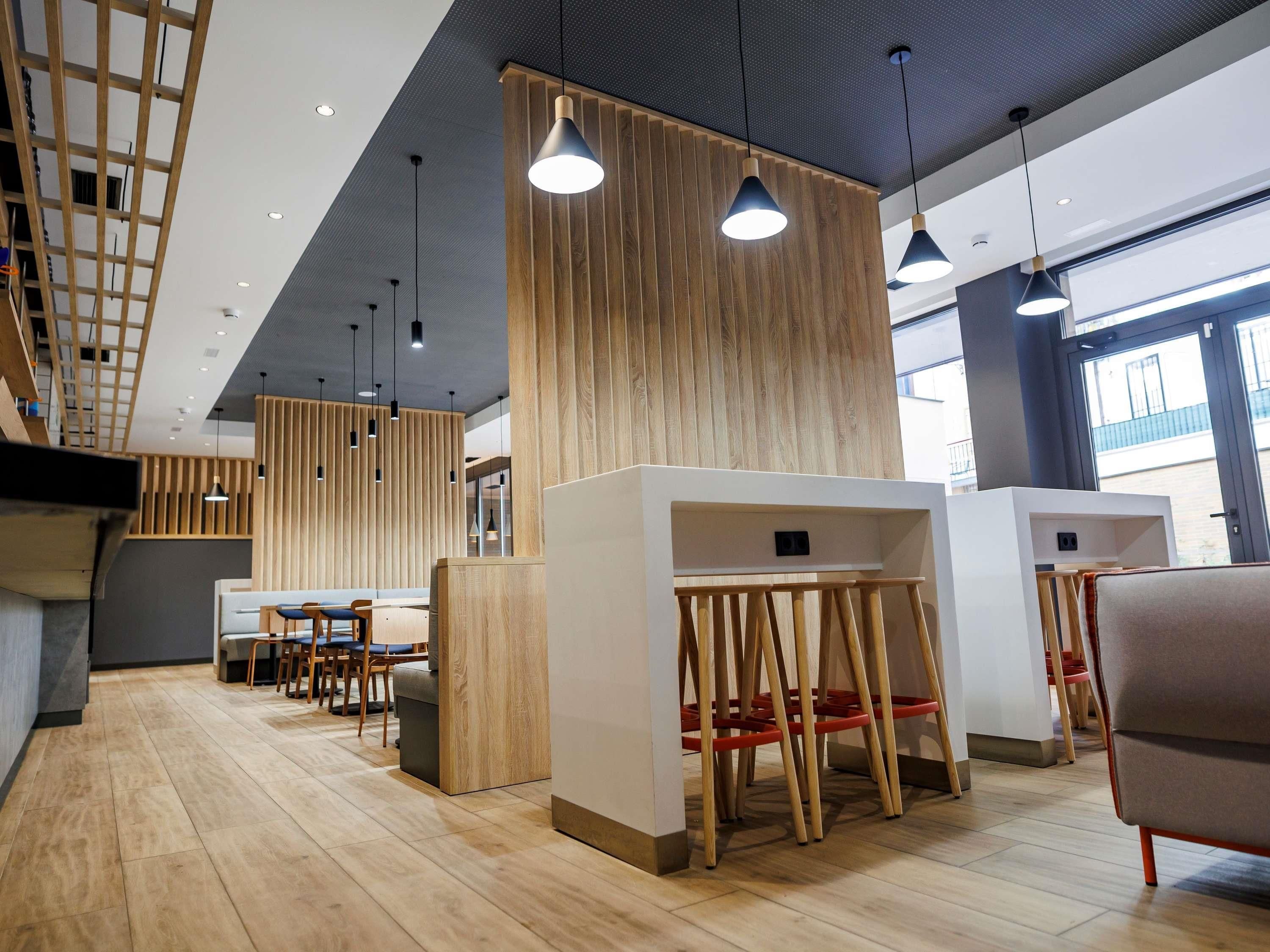 A modern interior with wooden accents, pendant lighting, and a seating area with tables and chairs.