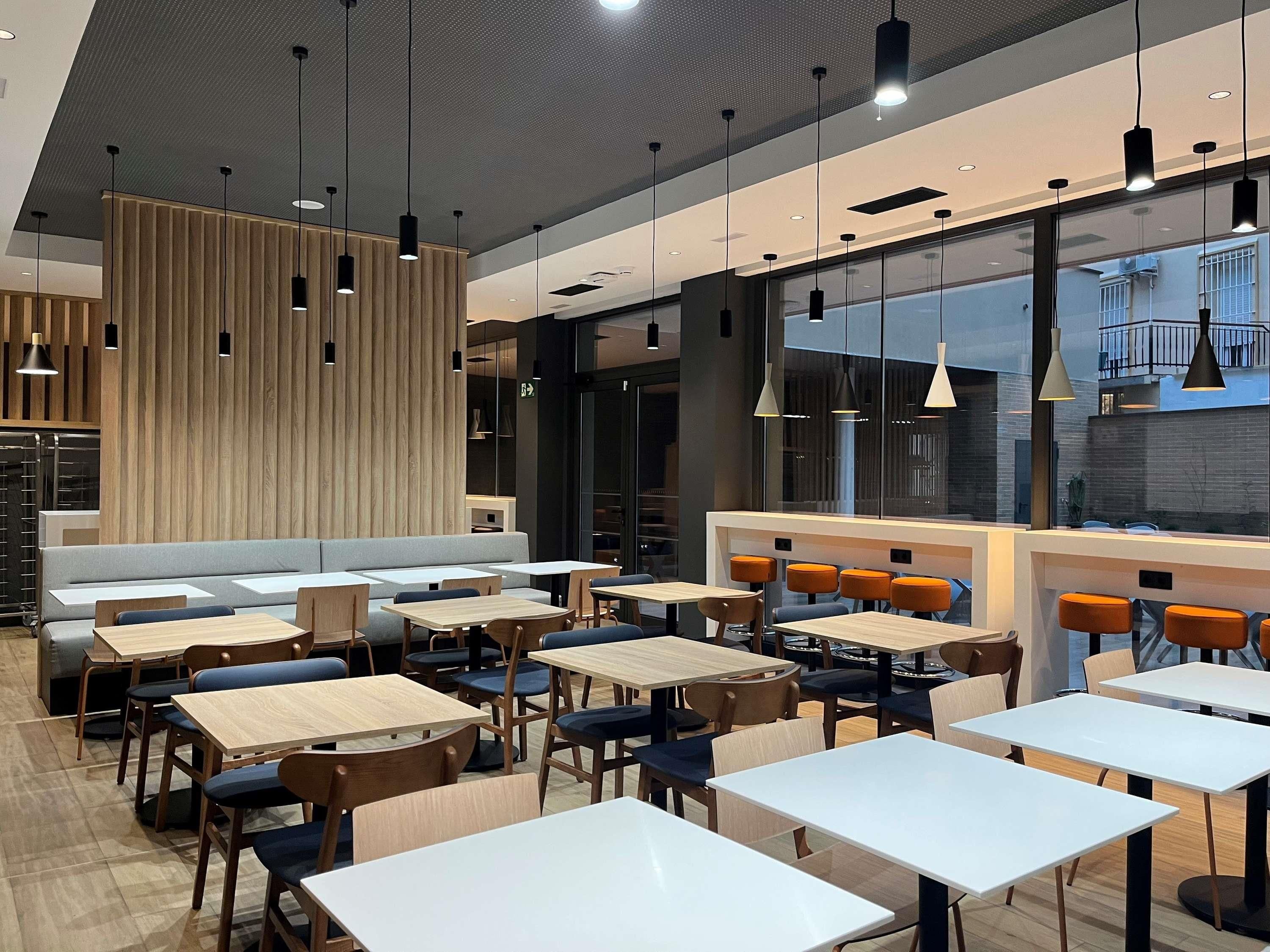 Un interior de restaurante moderno con mesas altas, sillas y una zona de estar.