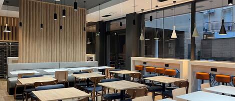 Un interior de restaurante moderno con mesas altas, sillas y una zona de estar.