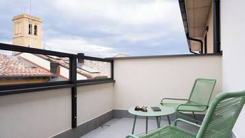 A balcony with a view of a tower, a table with chairs, and a pair of sunglasses on the table.