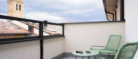 A balcony with a view of a tower, a table with chairs, and a pair of sunglasses on the table.