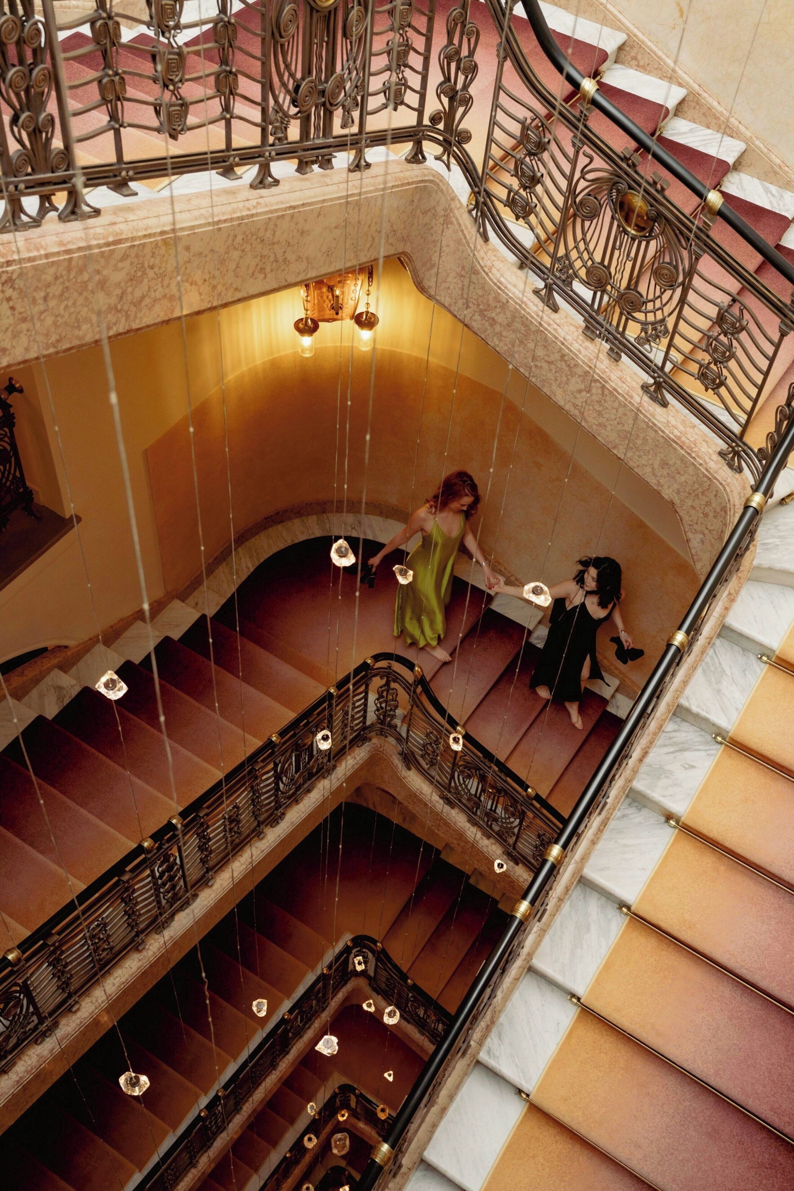 Un escalier à plusieurs niveaux, agrémenté de rampes en métal ouvragé et d’un lustre.