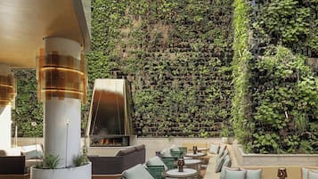 Un salón en la azotea con asientos al aire libre, un hogar de fuego y una pared de jardín vertical.