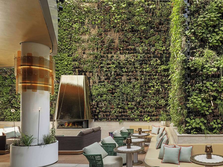 Un salón en la azotea con asientos al aire libre, un hogar de fuego y una pared de jardín vertical.