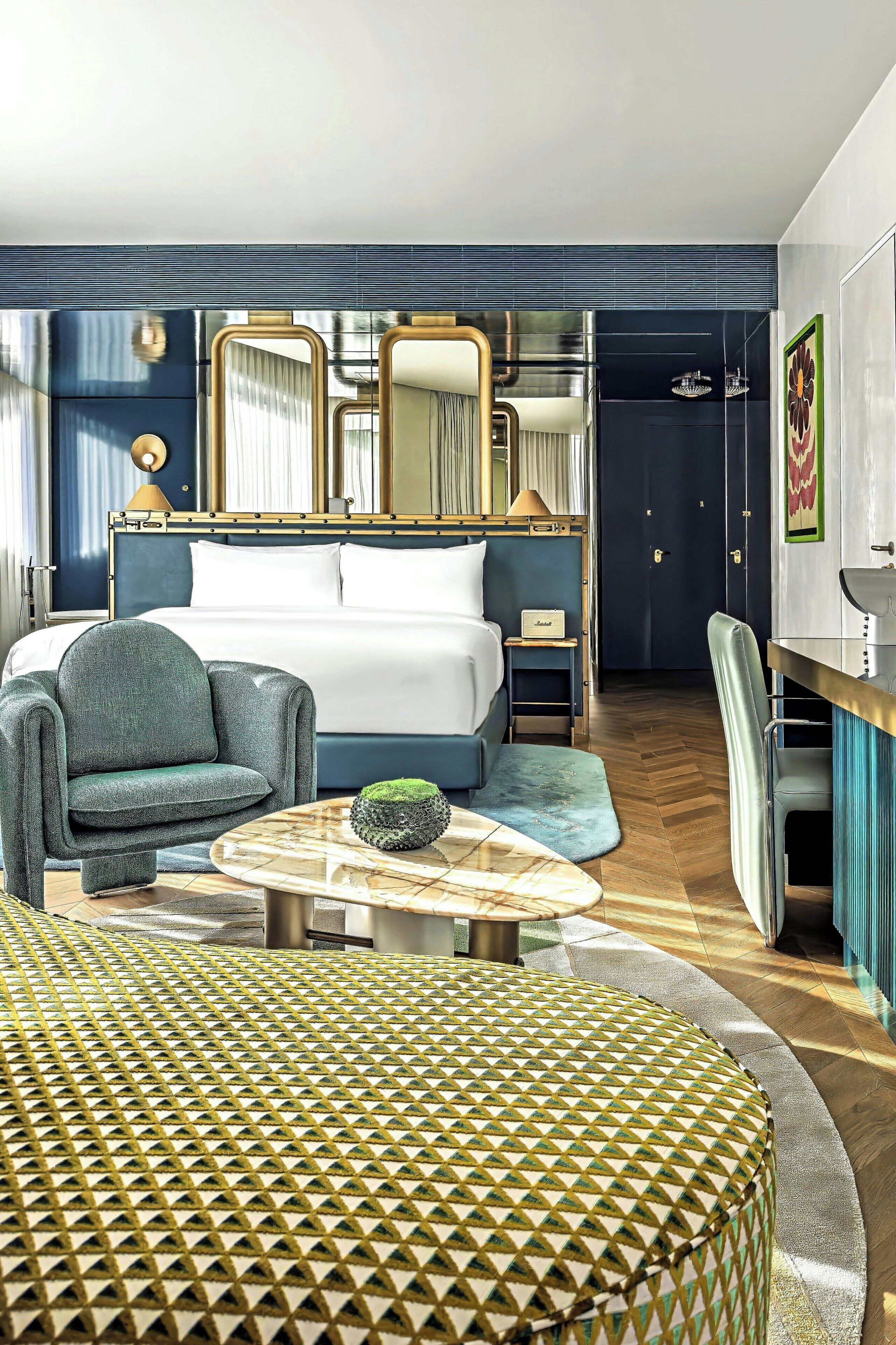 Una habitación de hotel moderna con una cama grande, una zona de estar con una mesa redonda y un escritorio con una silla.