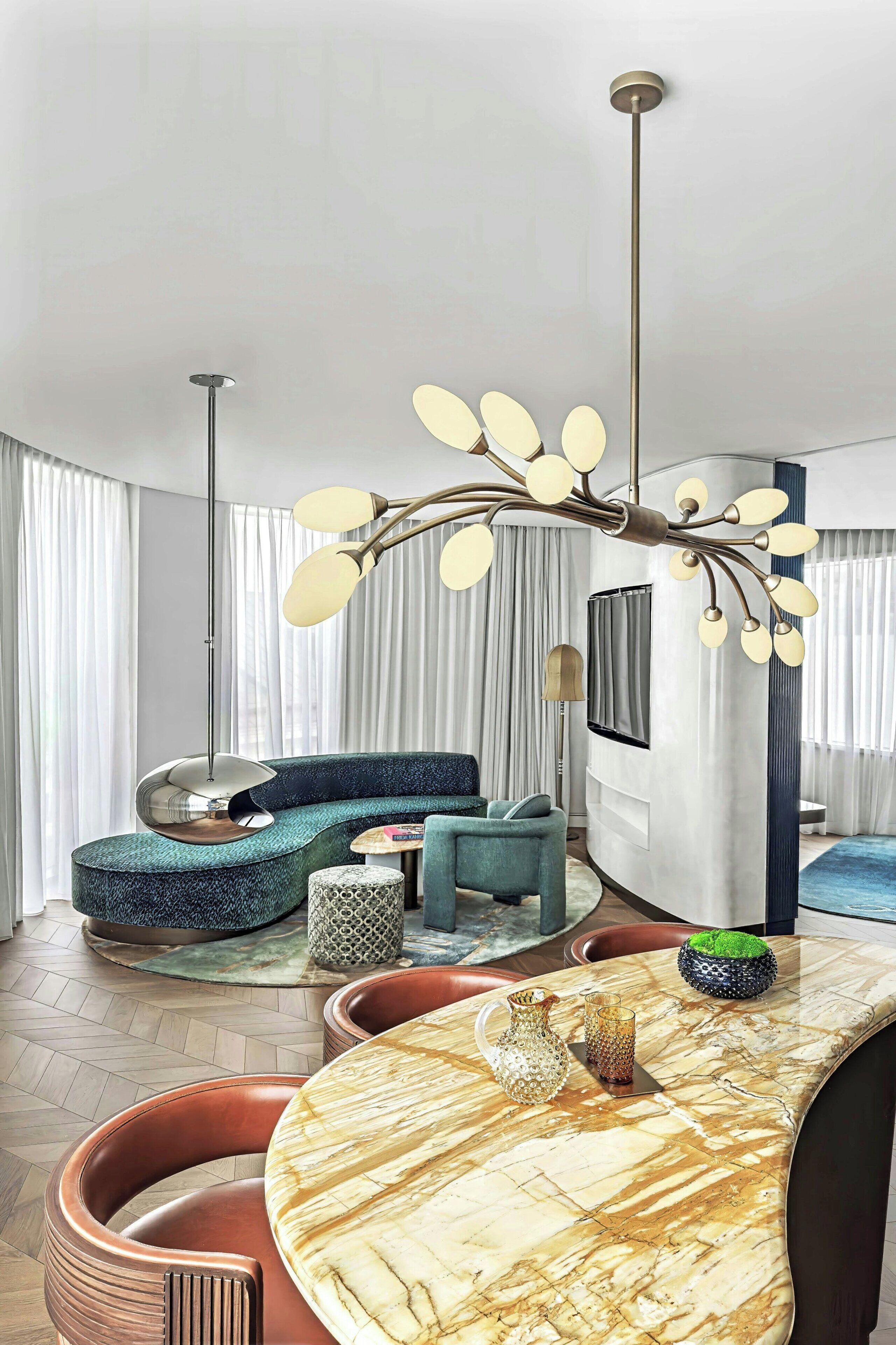 Een moderne woonkamer met een gebogen bank, een marmeren salontafel en een bijzondere kroonluchter.