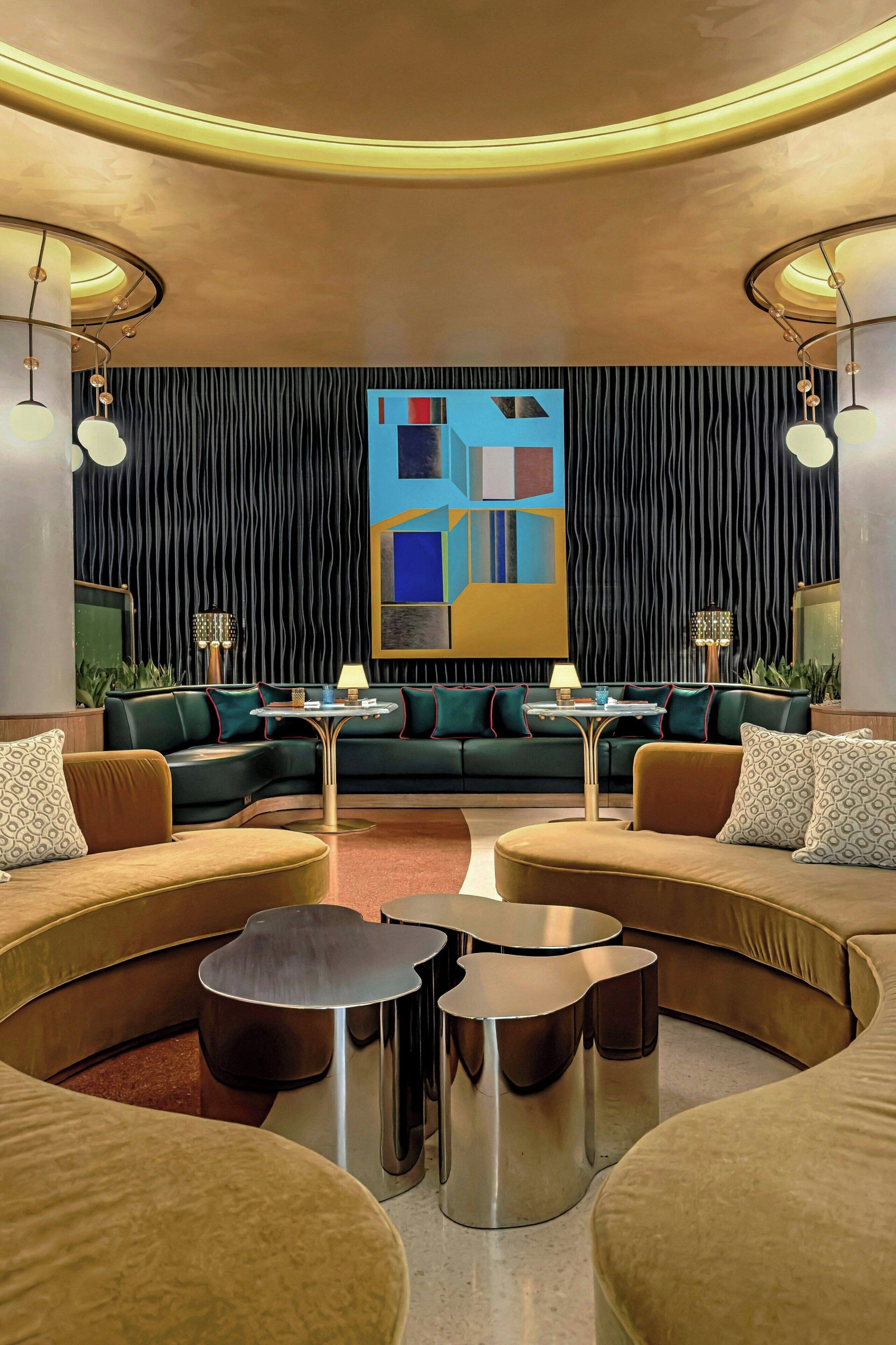 A modern lounge area with a curved sofa set, a round coffee table, and a large abstract painting on the wall.