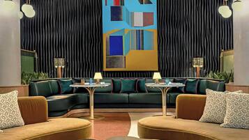A modern lounge area with a curved sofa set, a round coffee table, and a large abstract painting on the wall.