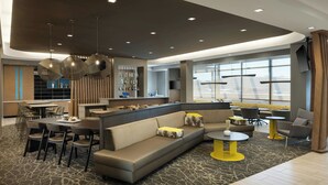 Eine moderne Hotelhalle mit großzügiger Sitzecke, einer Bar und einem Essbereich.