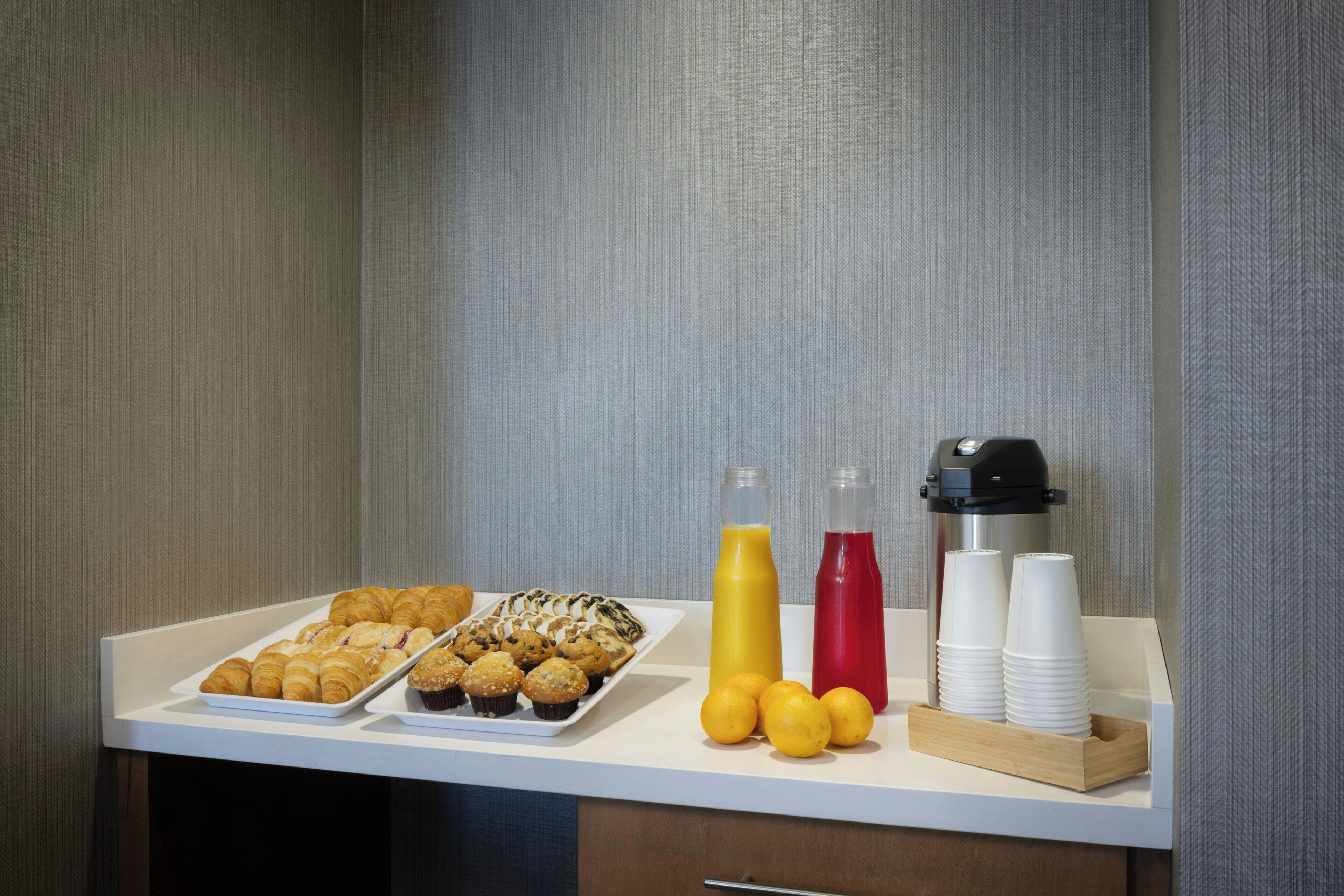 Ein Frühstücksbuffet mit Gebäck, Saft und Kaffeetassen.