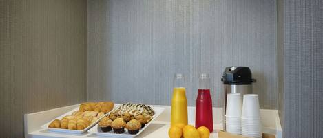 Ein Frühstücksbuffet mit Gebäck, Saft und Kaffeetassen.