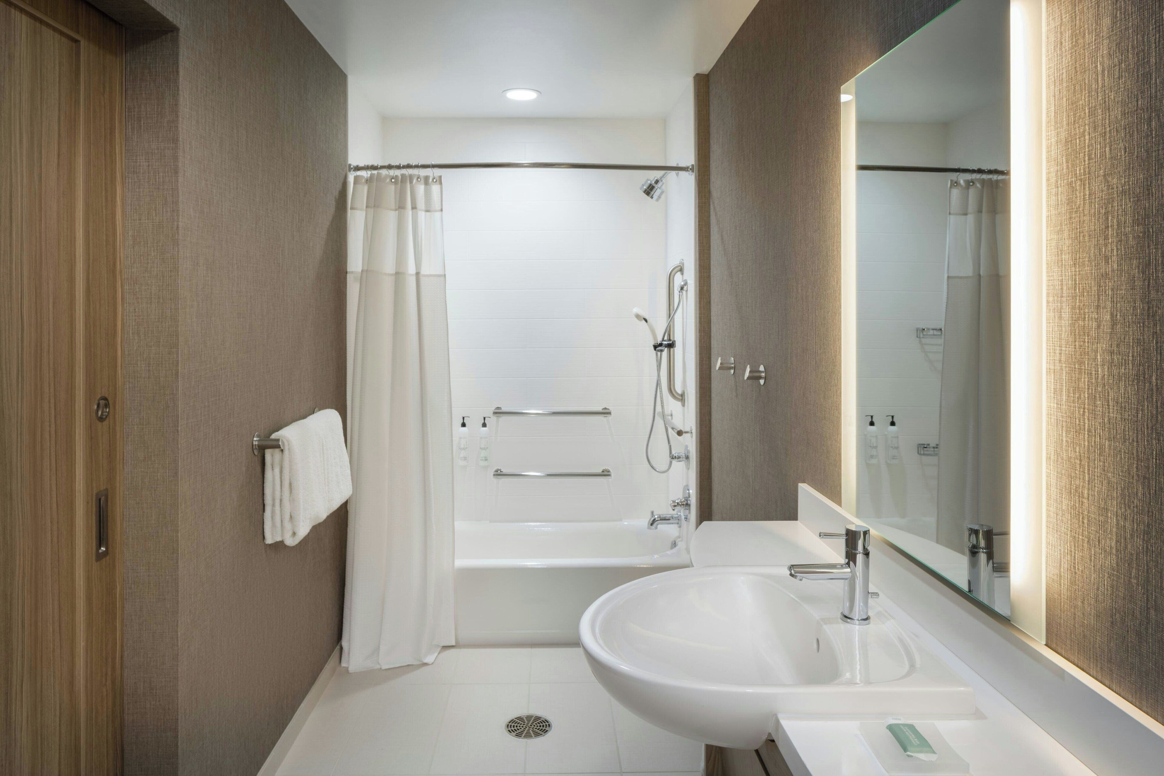 A modern bathroom with a bathtub, shower, and sink.