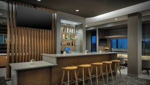 Eine moderne Bar mit einer Holztrennwand, einer Glasablage für Spirituosen und Holzhockern.