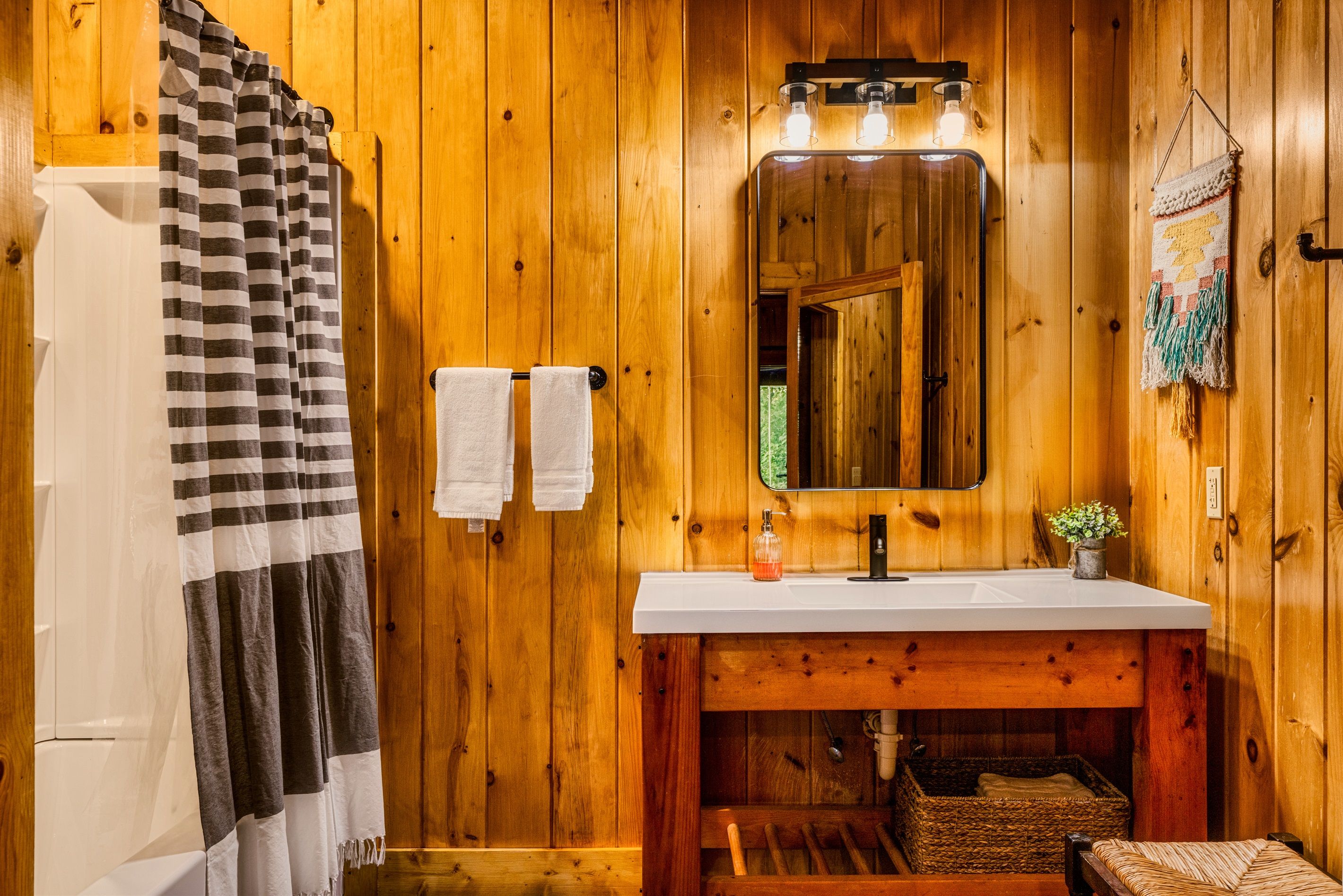 A wooden bathroom with a white sink, a mirror, and a towel rack.