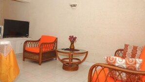 A living room with wicker furniture, a round table, and a flat-screen TV.