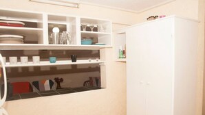 A kitchen with white cabinets, a white refrigerator, and shelves with dishes and glasses.
