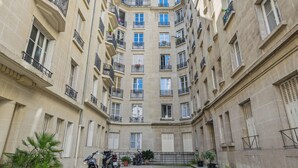 A multi-story building with balconies, large windows, and potted plants. - Terne Maillot - Gaston Bertandeau 1dbr (Paris)