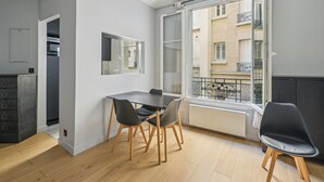 A modern apartment with a dining area, a kitchen, and a balcony with a view of the city. - Terne Maillot - Gaston Bertandeau 1dbr (Paris)