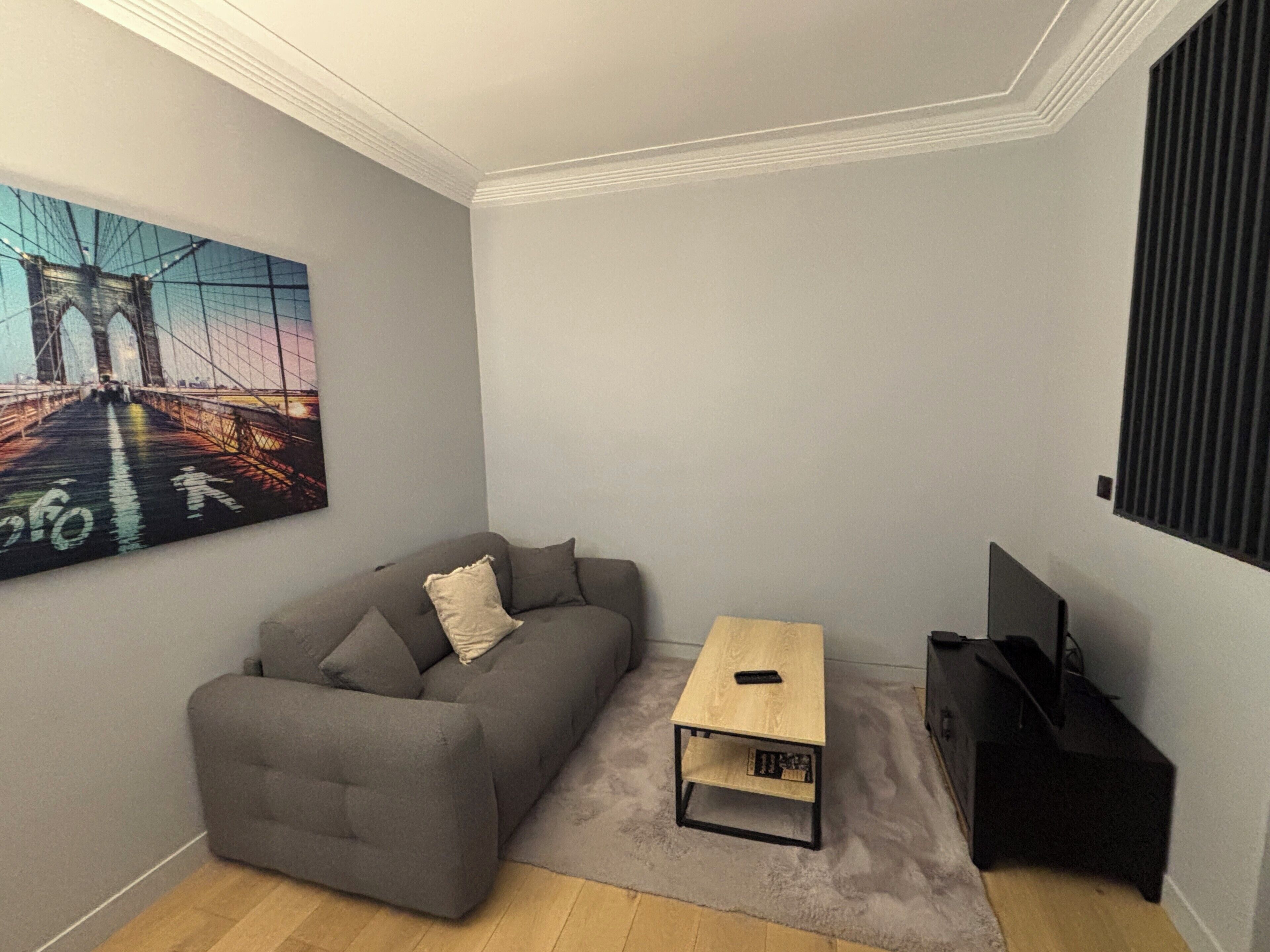 Un soggiorno con un divano grigio, un piccolo tavolino in legno e un mobile porta TV.