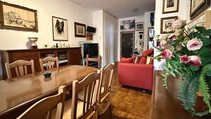 A dining area with a wooden table and chairs, a red sofa, and a vase of flowers. - SE092 - Senigallia, large four-room apartment with terrace (Senigallia)