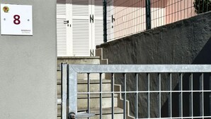 A gated entrance with a metal gate, a concrete wall, and a staircase leading to a building with a white shuttered door. - Palme 8 - Marcelli, three-room apartment with private garden, Residence Le Palme (Marcelli)